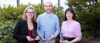 Three award winners standing in front of an outdoor landscape.
